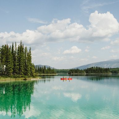 Two people in a red canoe on a bright turquoise lake.