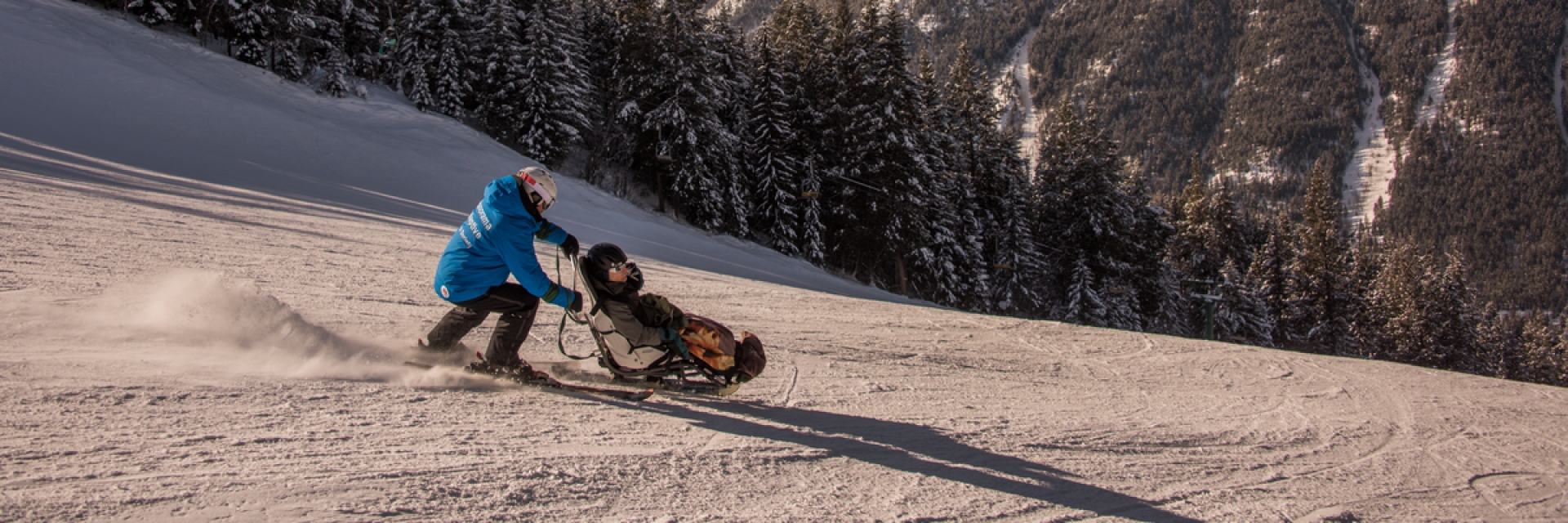 A person pushing another in an accessible skiing wheelchair