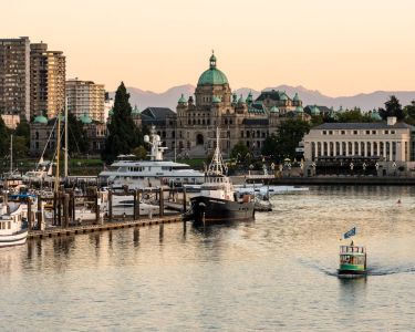 The inner harbour in Victoria with boats on water and sunset in distance.